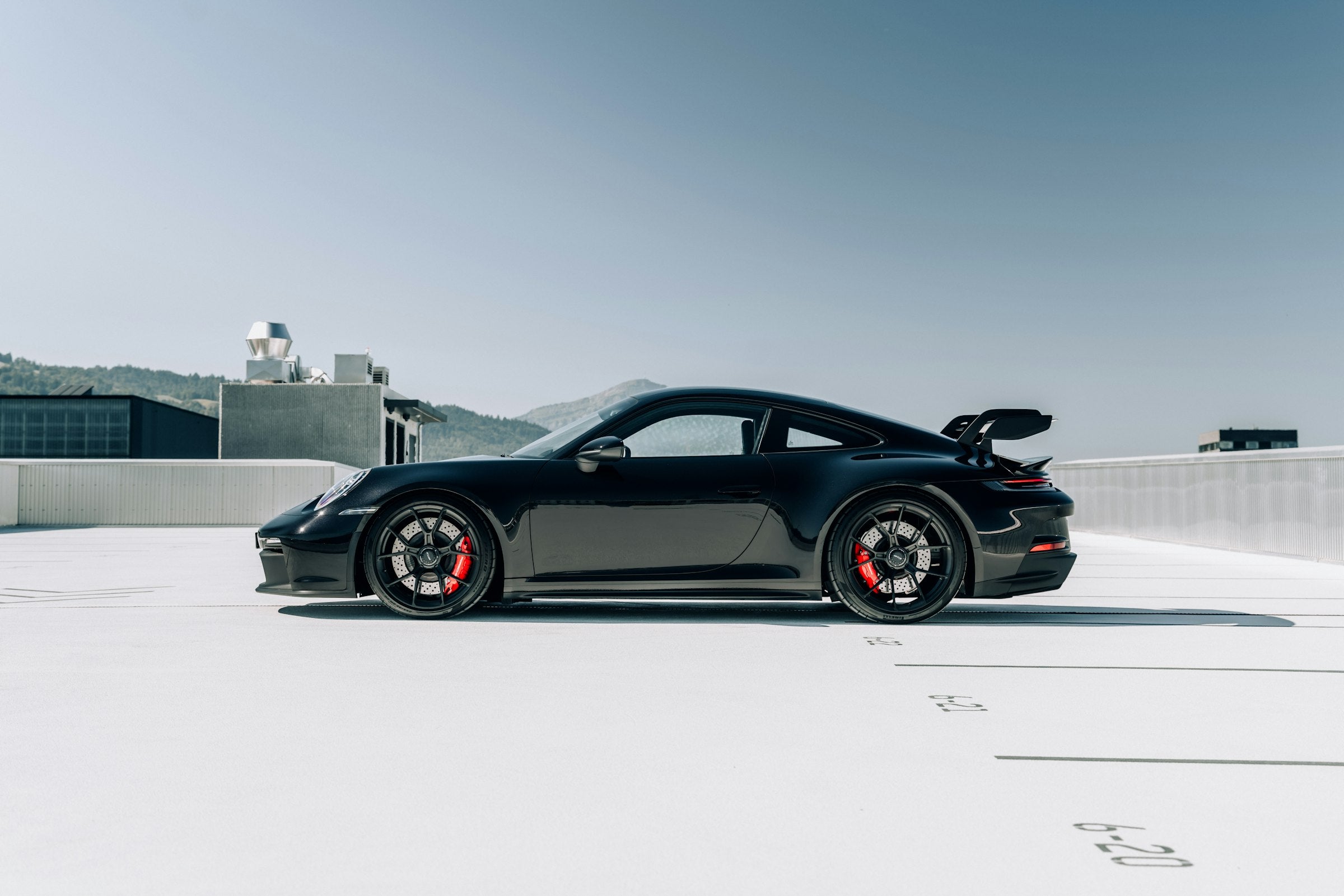A black 911 parked on an empty white rooftop