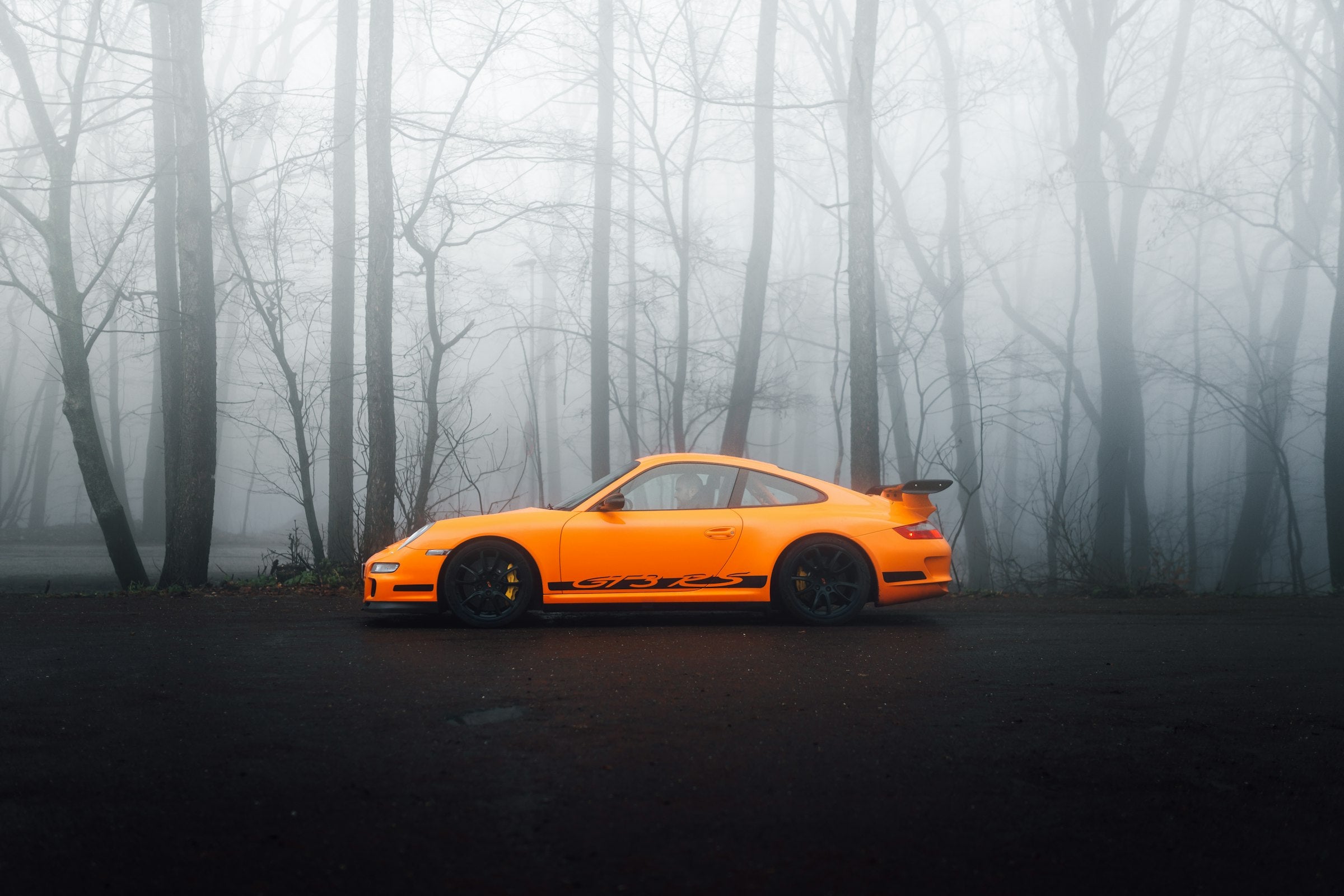 An orange 911 in a fogged winter forest